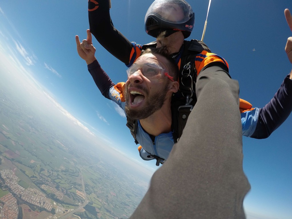 Homem participando de esportes de aventura no ar em salto duplo de paraquedas com instrutor