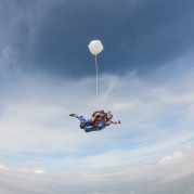 Pessoa saltando de paraquedas em céu azul
