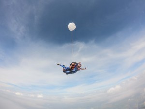 Pessoa saltando de paraquedas em céu azul