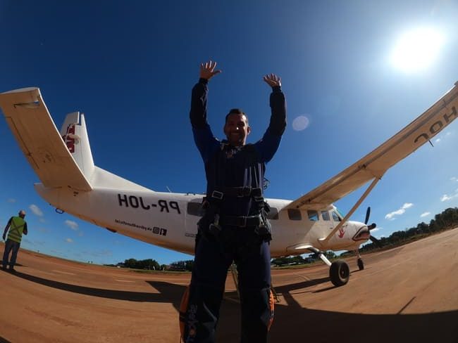 homem posando para foto na frente de um avião de paraquedismo
