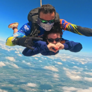 Instrutor de paraquedismo e aluna em queda livre durante salto duplo de paraquedas, escolha ideal para sua programação de férias