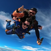 Instrutor de paraquedismo e aluna praticando experiências radicais em queda livre durante salto duplo de paraquedas