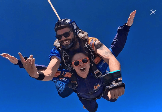 Instrutor de paraquedismo e aluna em queda livre, praticando esportes de aventura