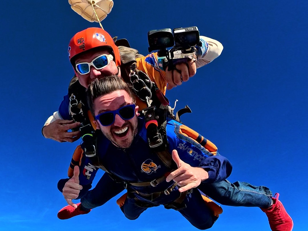 Instrutor de paraquedismo e aluno em queda livre durante salto duplo de paraquedas