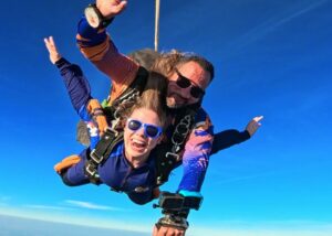 Instrutor e aluna em queda livre durante salto de paraquedas