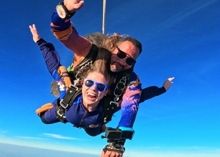 Instrutor e aluna em queda livre durante salto de paraquedas