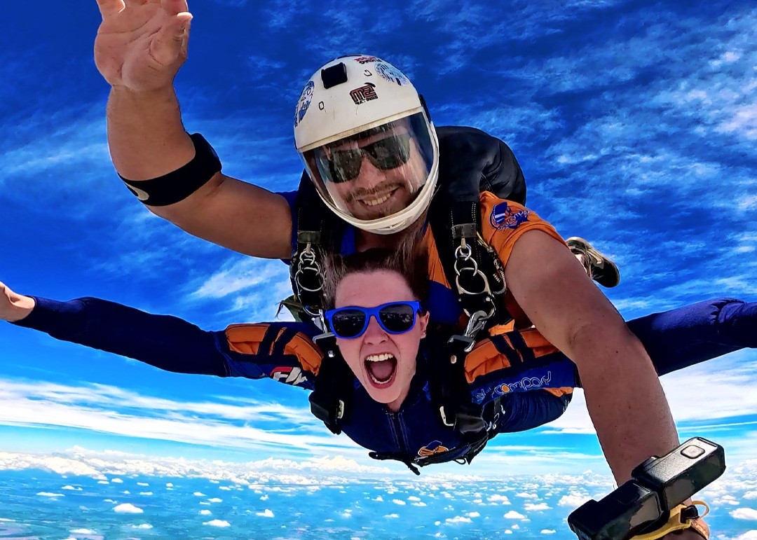 Instrutor e aluna durante queda livre após pular de paraquedas