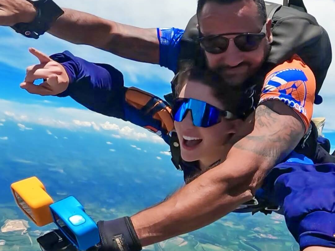 Instrutor de paraquedismo e aluna em queda livre após pular de paraquedas