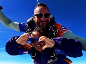 Instrutor de paraquedismo e aluna em queda após pular de paraquedas.